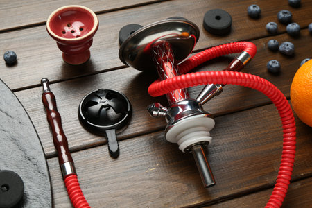 Traditional hookah parts, charcoal rings and blueberries on wooden table