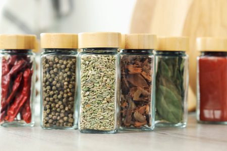 Many different aromatic spices in jars on table indoors, closeup
