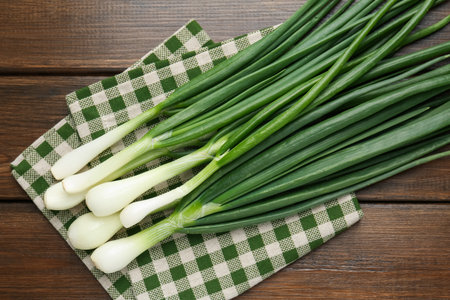Fresh ripe green onions and towel on wooden table, top viewの写真素材