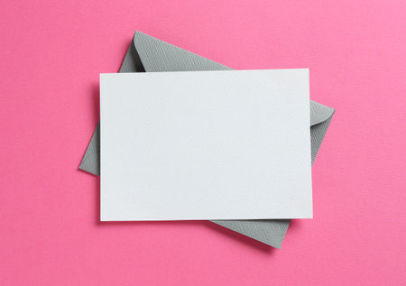 Blank invitation card and envelope on pink background, top view. Space for design