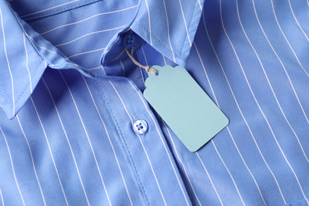 Cardboard tag on light blue shirt, top viewの写真素材