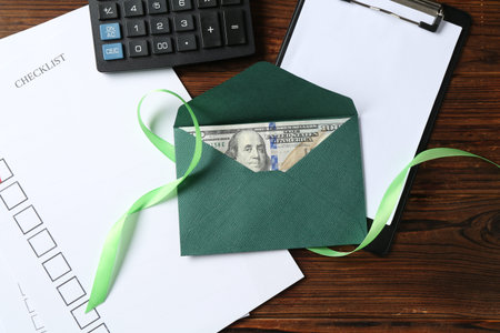 Money bonus. Envelope with dollar banknote, clipboard, checklist, ribbon and calculator on wooden...