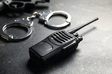 Walkie talkie, handcuffs and gun on dark table, closeup. Police equipmentの写真素材