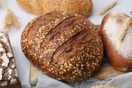 Fresh bread loaves and spikes on white table, closeup