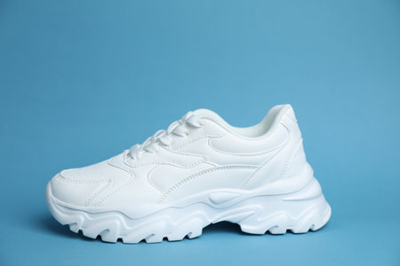 One stylish white sneaker on light blue backgroundの写真素材