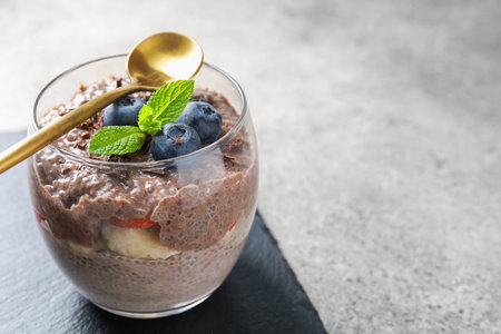 Delicious chocolate pudding with chia seeds and blueberries in glass on light gray table, closeup. Space for textの写真素材