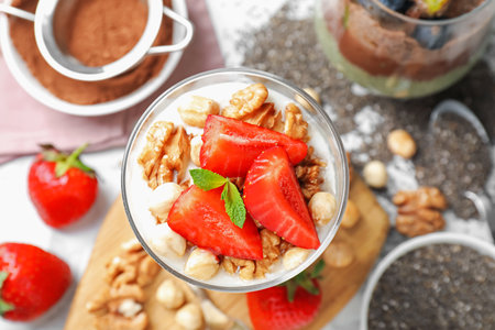Delicious chocolate pudding with chia seeds, strawberries, yogurt and nuts in glass on white table, flat layの写真素材