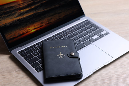 Passport and laptop on light wooden table, closeup
