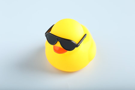Cute rubber duck with sunglasses on white background, closeup