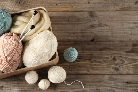 Felting wool and knitting yarn with needles on wooden table, top view. Space for textの写真素材