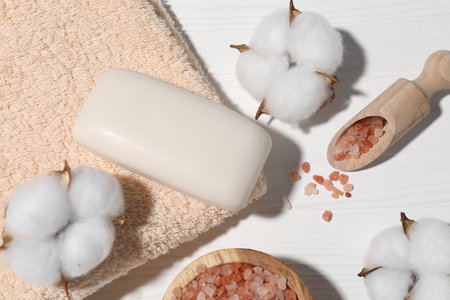 Soap bar, sea salt, cotton flowers and towel on white wooden table, flat layの写真素材