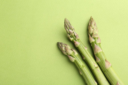 Fresh ripe raw asparagus on green background, flat lay. Space for textの写真素材