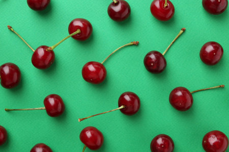 Fresh ripe cherries on green background, flat lay