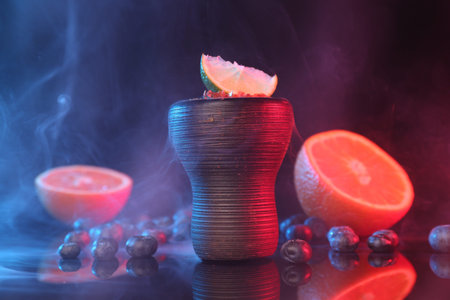 Hookah bowl with smoke and fruits on black table in neon lights, closeupの写真素材