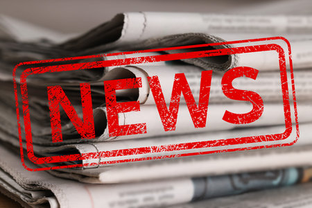 Red News stamp and many newspapers on table, closeupの写真素材