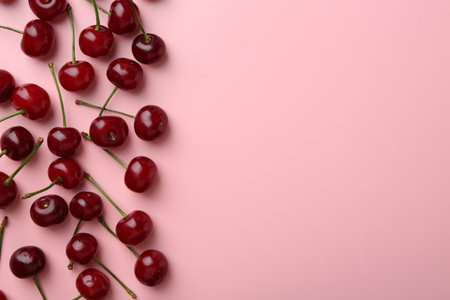 Fresh ripe cherries on pink background, flat lay. Space for textの写真素材