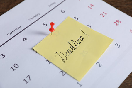 Sticky note with word Deadline and calendar on table, closeupの写真素材
