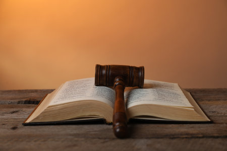 Judge's gavel and Bible on wooden table against pale orange background, closeupの写真素材