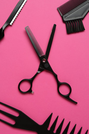 Different hairdresser's tools on pink background, flat lay
