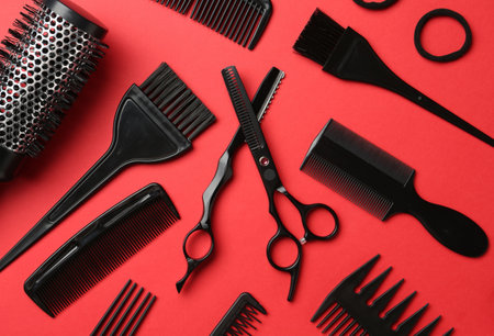 Different hairdresser's tools on red background, flat lay