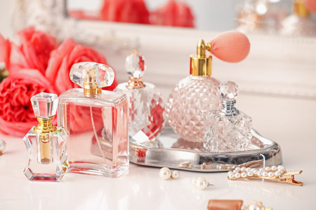 Bottles of different perfumes, accessories and flowers on dressing table indoors, closeup