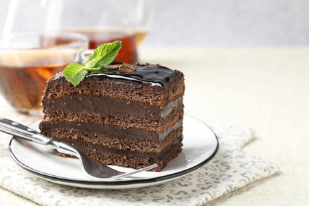 Piece of chocolate cake served with mint, fork and tea on white table, closeup. Space for textの写真素材