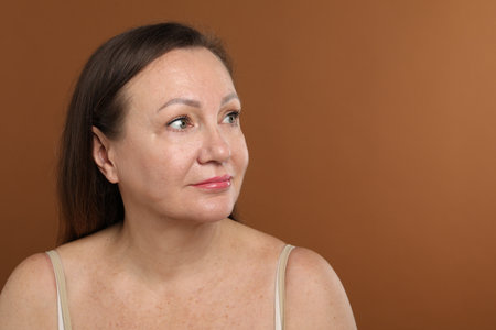 Woman before cosmetic procedure on brown background. Space for textの写真素材