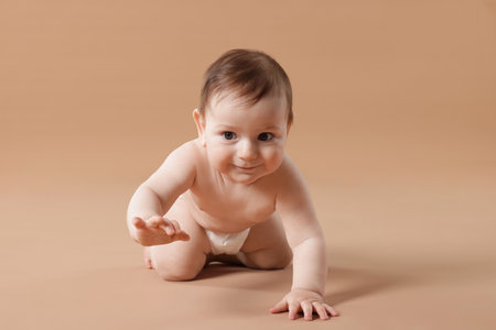 Cute little baby crawling on beige backgroundの写真素材