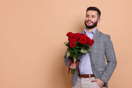 Happy man with bouquet of red roses on beige background, space for textの写真素材