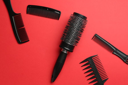Different hairdresser's tools on red background, flat lay