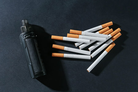 Electronic smoking device and cigarettes on dark table, flat layの写真素材