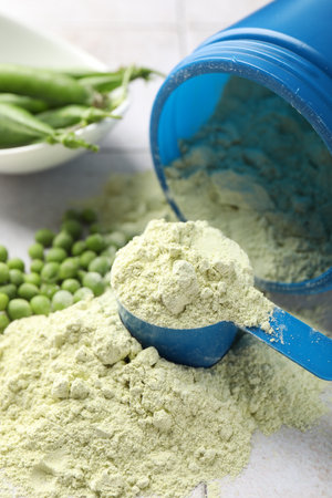Protein powder and green peas on light tiled table, closeupの写真素材