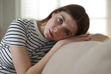 Depressed teenage girl on sofa at homeの写真素材