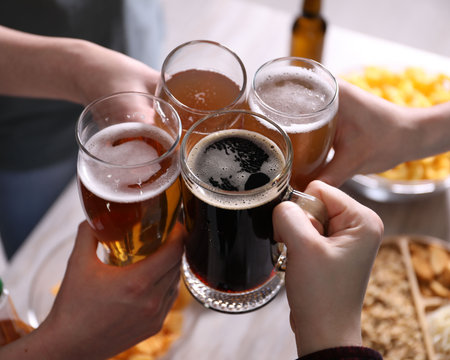Friends clinking glasses of beer at table, closeupの写真素材