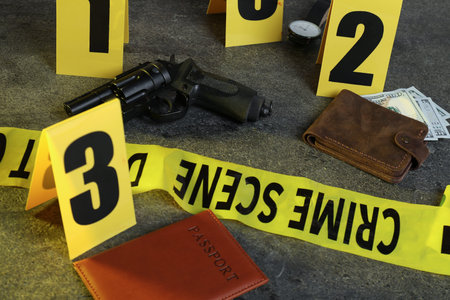 Forensic expert. Yellow crime scene tape, markers and evidences on grey table, closeupの写真素材