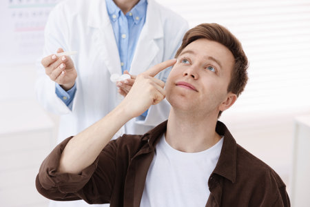Young man putting on contact lenses in ophthalmologist officeの写真素材