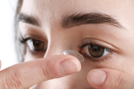 Woman putting in contact lens on white background, closeupの写真素材