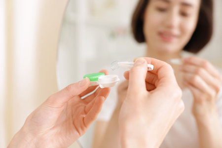 Woman taking contact lens out of case indoors, closeupの写真素材