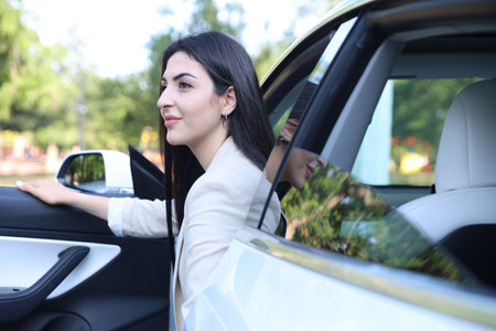 Woman getting out of modern car outdoors
