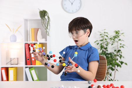 Emotional boy with DNA structure model at desk indoorsの写真素材