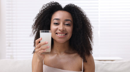 Beautiful Brazilian woman with glass of collagen water indoorsの写真素材