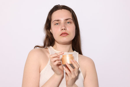 Portrait of beautiful woman with jar of skincare product on light background, closeupの写真素材