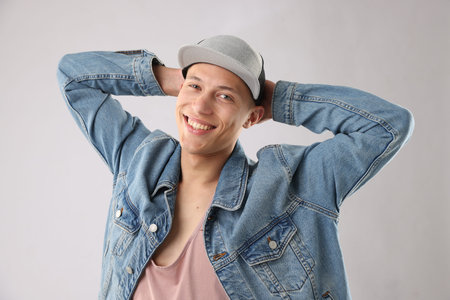 Young man in stylish baseball hat on light gray backgroundの写真素材