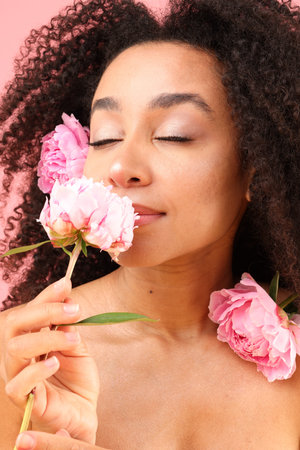 Beautiful Brazilian woman with peonies on pink background, closeupの写真素材