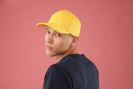 Young man in stylish baseball hat on pink backgroundの写真素材
