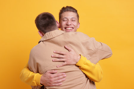 Friends hugging each other on orange backgroundの写真素材