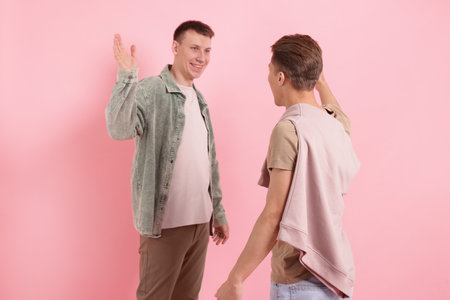 Friends welcoming each other on pink backgroundの写真素材