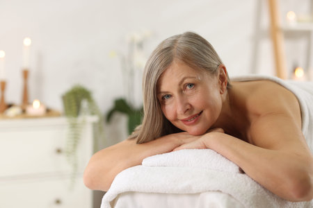 Senior woman relaxing on massage couch in spa salonの写真素材