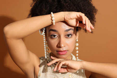 Fashionable portrait of beautiful Brazilian woman in stylish outfit on light brown background, closeupの写真素材