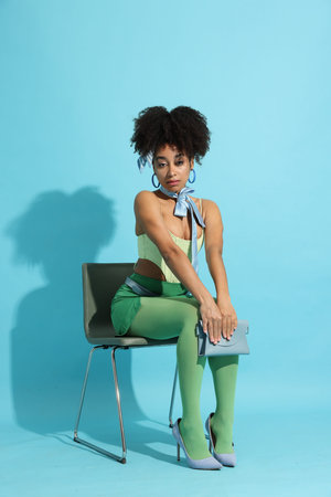Fashionable portrait of beautiful Brazilian woman in stylish outfit on light blue backgroundの写真素材